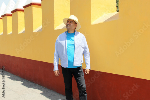Dark-skinned Latino 40-year-old man with a hat walks as a tourist through the streets of a provincial town in Latin America, knows and discovers while traveling