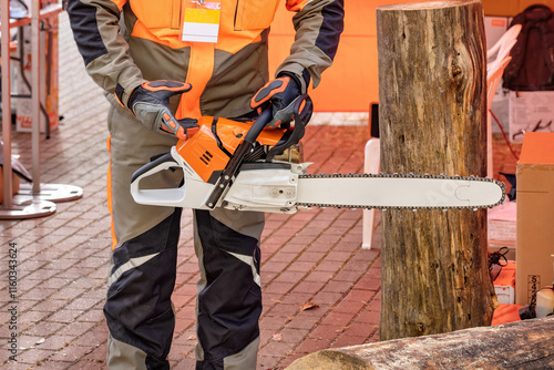 Obraz na płótnie Experienced lumberjack demonstrates proper chainsaw handling at outdoor woodworking event w salonie