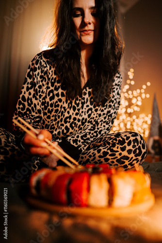 Warm evening with a woman enjoying fresh sushi in bed wearing cozy pajamas under soft lighting