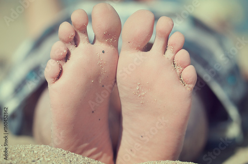 Close-up of the soles of a man's feet on a sandy beach photo