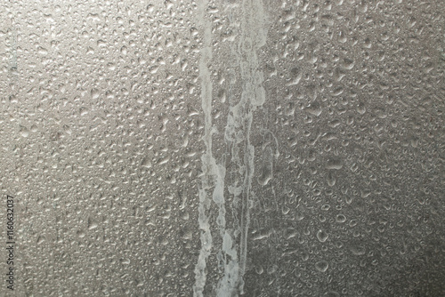 Limescale trails from hard water issue and water drops, on metallic gray  plastic shower wall, abstract texture