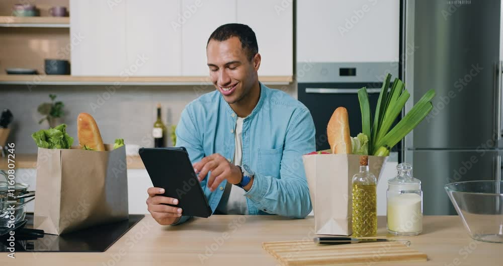 Man using tablet pc mobile apps, modern internet online information technology in kitchen during breakfast. Man using tablet pc mobile apps, modern internet online information technology in kitchen during breakfast.