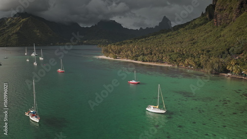 Stunning aerial view sailboats yachts in Opunohu bay's turquoise waters, lush green vegetation and dramatic mountains in Moorea, French Polynesia. Wild nature paradise, exotic summer luxury travel photo