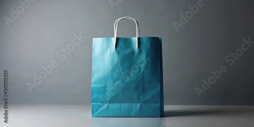 A teal paper shopping bag with white handles stands against a gray backdrop, ready to be filled with gifts and goodies. photo