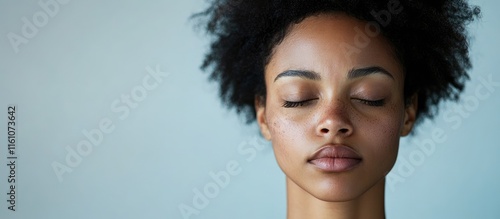 Sleep deprived young woman with visible dark circles under eyes expressing fatigue against a soft grey background with space for text.