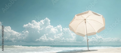 Windblown white beach umbrella on tranquil shoreline with clear sky and empty space for text ideal for summer vacation promotional material photo