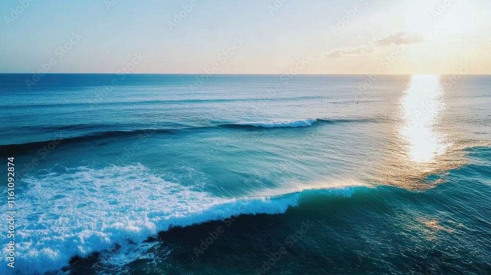 Obraz premium Gentle ocean waves create a serene rippling surface reflecting warm sunlight and a tranquil sky at sunset over the horizon.