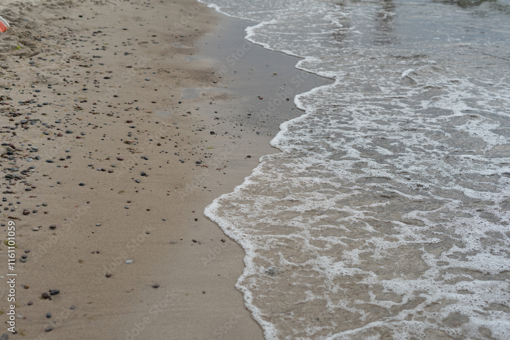 Gentle waves washing onto a sandy beach with scattered pebbles.
Gentle waves washing onto a sandy beach with scattered pebbles.