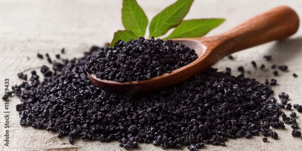 Black hawaiian sea salt pile with wooden spoon and bay leaves on rustic surface Black hawaiian sea salt pile with wooden spoon and bay leaves on rustic surface