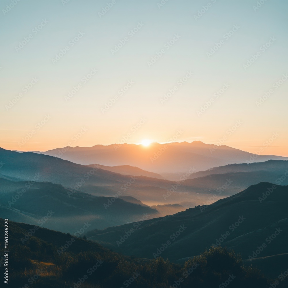 Fototapeta premium Serene sunrise over misty mountain range.