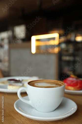 Aromatic cappuccino, delicious cottage cheese pancakes and dessert served on wooden table in cafe, closeup photo