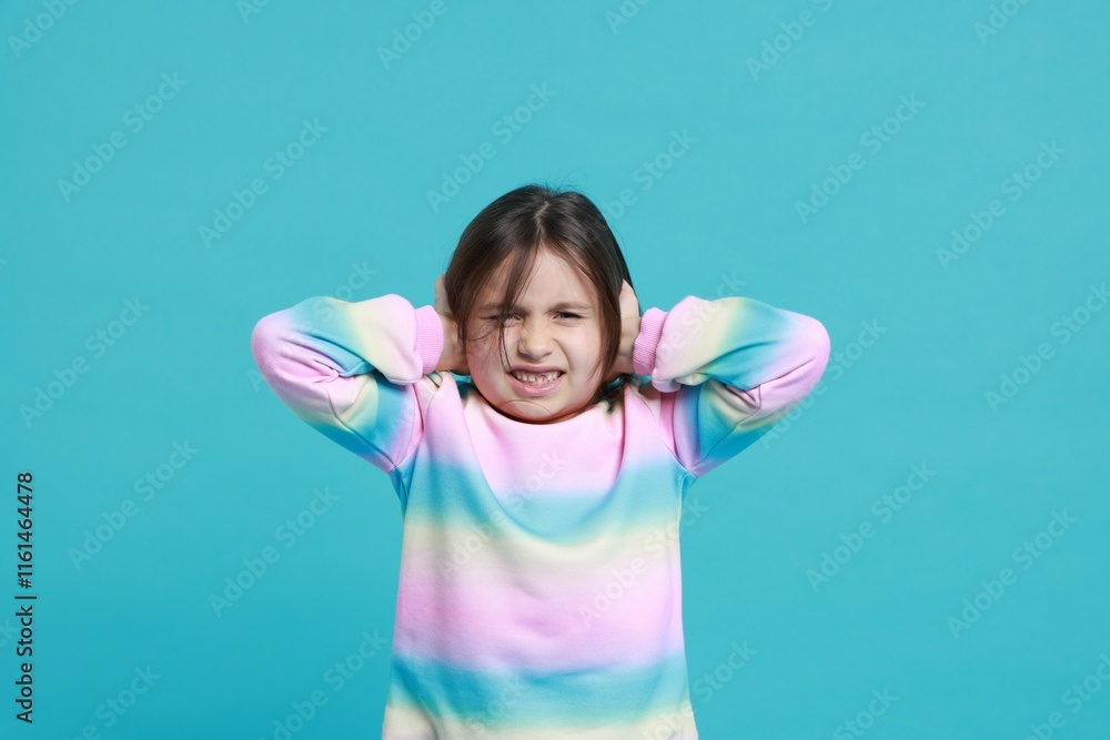 Annoyed little girl covering her ears from loud sound on light blue background Annoyed little girl covering her ears from loud sound on light blue background
