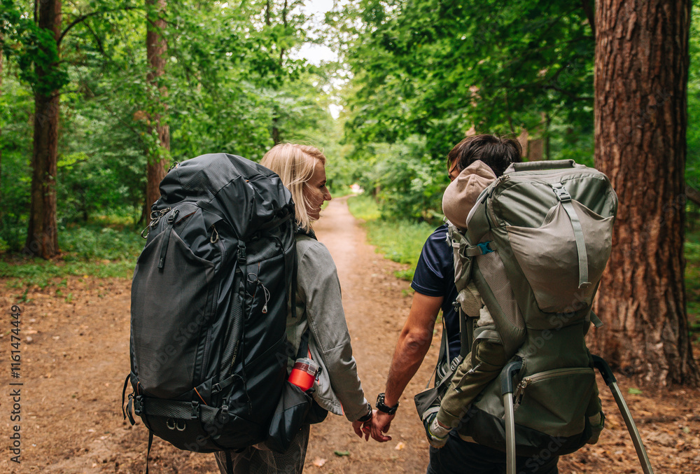 family with a small child in a travel backpack baby carrier. go camping with a tent and backpacks family with a small child in a travel backpack baby carrier. go camping with a tent and backpacks