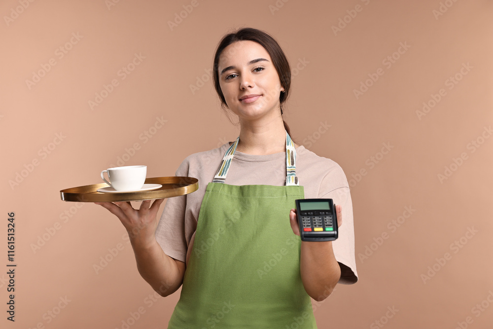 Girl in apron with cup of coffee and payment terminal on pale brown background. Work for teenagers