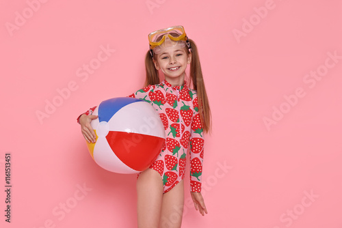 Happy girl in beachwear with diving mask and inflatable ball on pink background photo