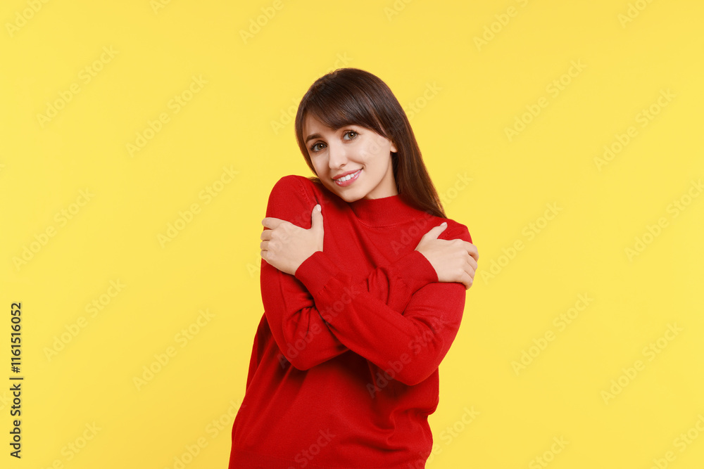 Young woman hugging himself on yellow background Young woman hugging himself on yellow background