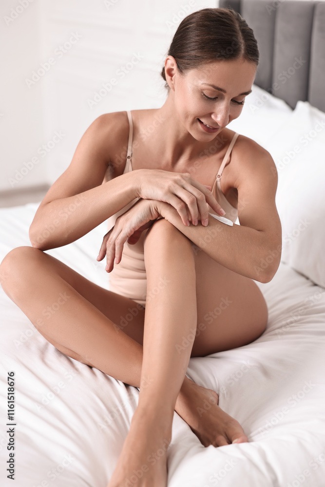 Smiling woman with perfect skin applying cream onto hand on bed. Body care Smiling woman with perfect skin applying cream onto hand on bed. Body care