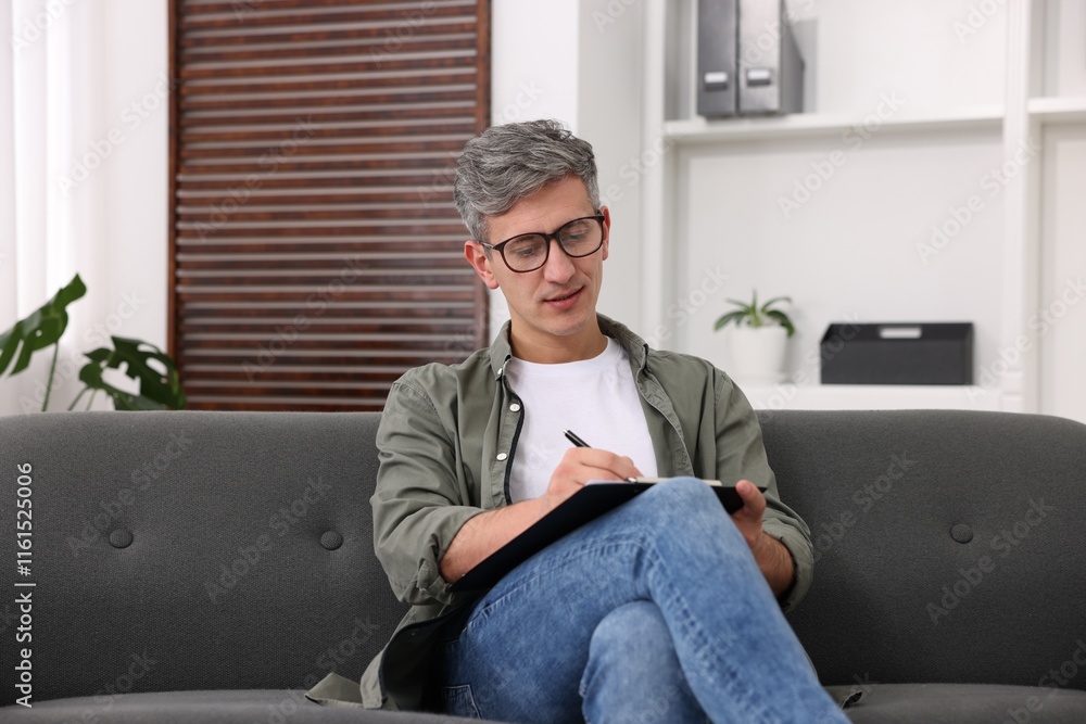 Professional psychologist with clipboard on sofa in office Professional psychologist with clipboard on sofa in office