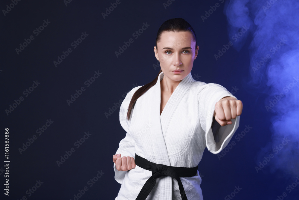 Karate fighter in kimono on dark blue background Karate fighter in kimono on dark blue background