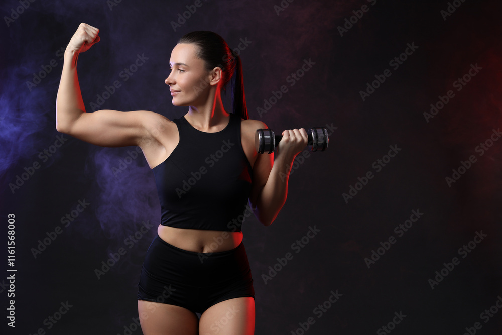 Woman exercising with dumbbell in smoke on dark background, space for text Woman exercising with dumbbell in smoke on dark background, space for text