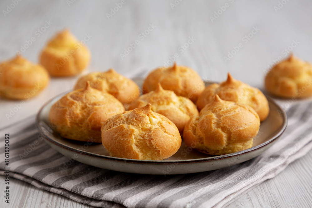 Homemade French Mini Cream Puffs on a Plate, side view. Homemade French Mini Cream Puffs on a Plate, side view.