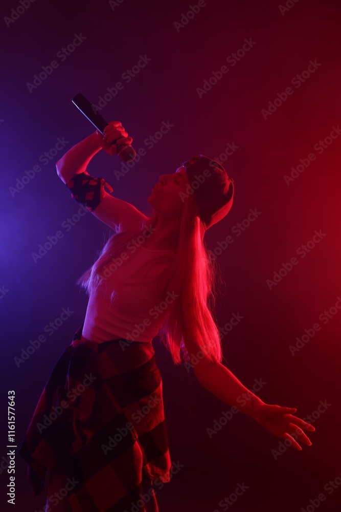 Fototapeta premium Talented singer performing on dark background with color lights