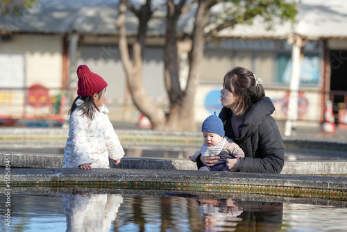 A five-month-old baby, a three-year-old girl, and a Japanese woman in her 30s spend a cold winter afternoon in front of a pond in a park in Hakata City, Fukuoka Prefecture. photo