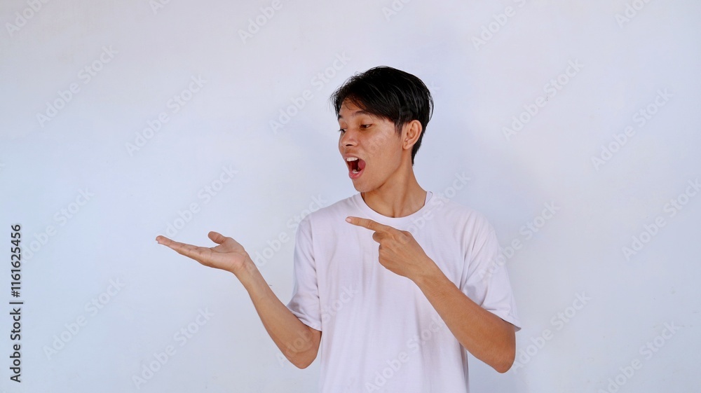 handsome asian young man with shocked expression wearing white shirt pointing gesture and looking at empty palm