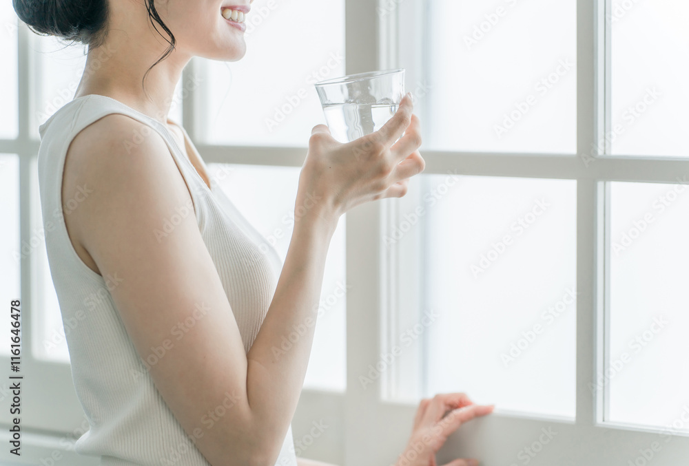 家で水・ミネラルウォーター・白湯をコップで飲むリラックスした女性
家で水・ミネラルウォーター・白湯をコップで飲むリラックスした女性