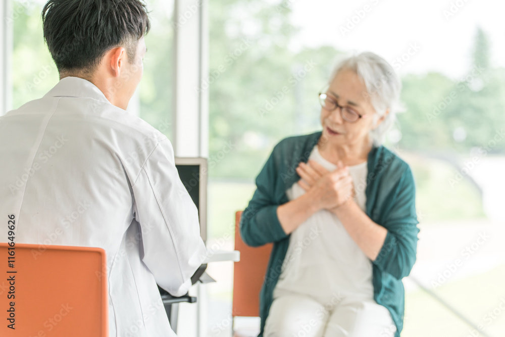 Obraz premium 病院・介護施設で医師に病状を伝えるシニア女性を問診する男性医師(診療・診察・人間ドック・健康診断)