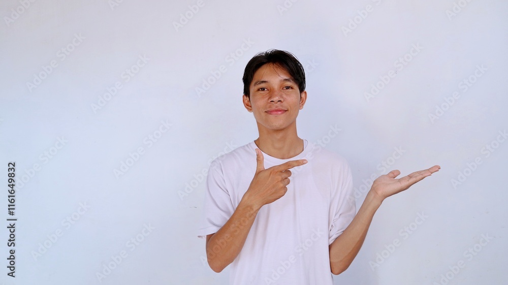 handsome asian young man smiling expression wearing white shirt gesture pointing empty palm with isolated white background handsome asian young man smiling expression wearing white shirt gesture pointing empty palm with isolated white background
