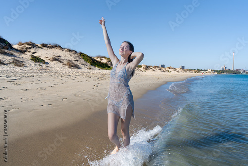 Chica joven muy a gusto y relajada en la playa junto al mar, con un sensacional día de vacaciones en verano soleado y con cielo azul. photo