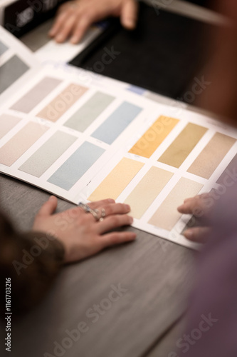 Catalog with palette of pastel interior design paints on table. Client consultation in design studio. People choose paint samples for walls. Varnishes, plasters, backgrounds, wallpaper, facades.