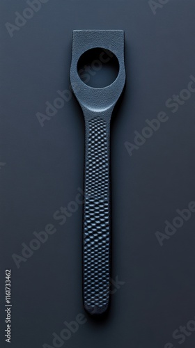 Black kitchen utensil with central hole and textured handle photo