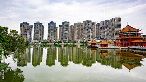 Skyscraper-City in the background and a Buddhist temple with a bridge over the lake in Yunnan Province photo