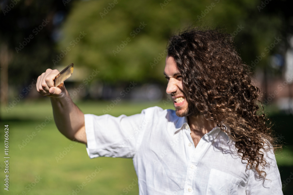 Outdoor portrait of man upset about not being able to comb his long hair Outdoor portrait of man upset about not being able to comb his long hair