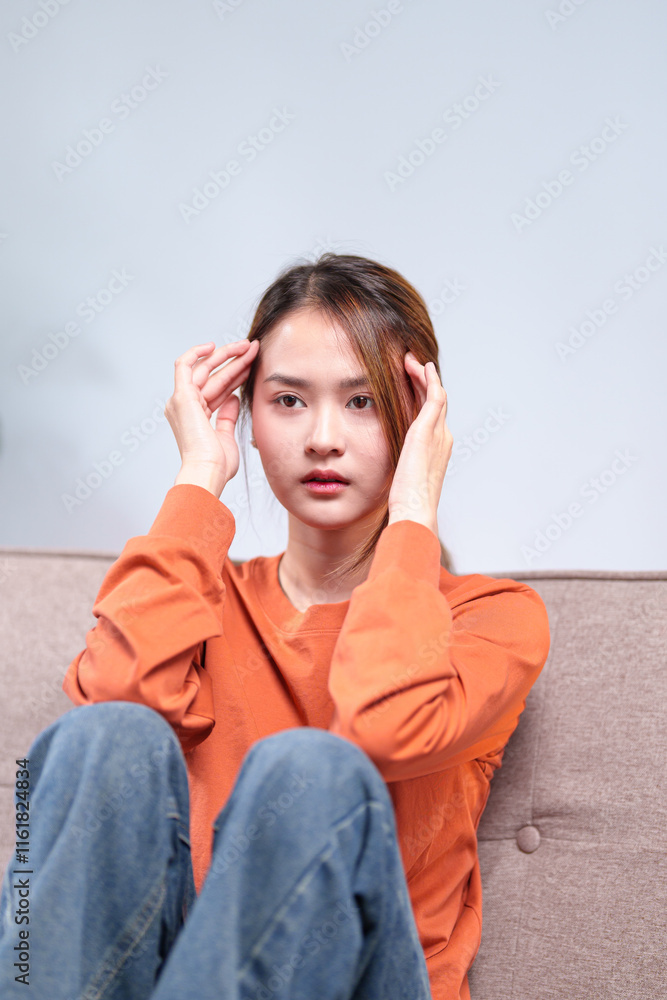 A thoughtful young woman seated on a sofa, resting her head on her hand, appearing deep in contemplation A thoughtful young woman seated on a sofa, resting her head on her hand, appearing deep in contemplation