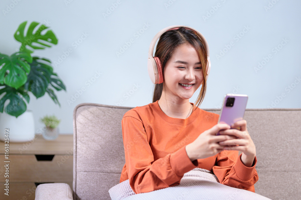 A young woman wearing headphones, smiling while using her smartphone, immersed in an engaging mobile experience A young woman wearing headphones, smiling while using her smartphone, immersed in an engaging mobile experience