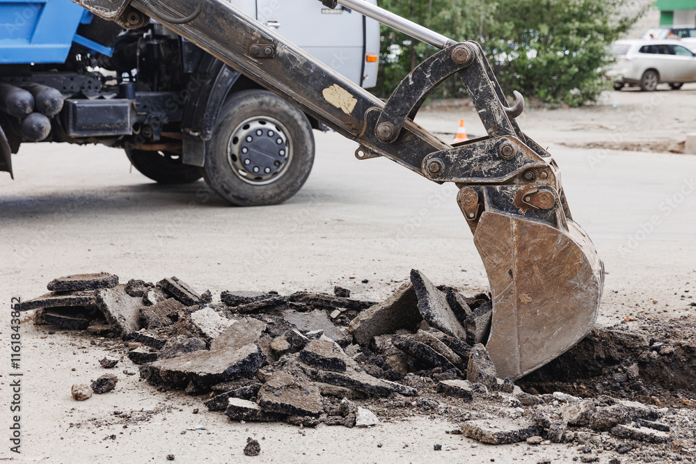 Fototapeta premium Construction site excavator breaking pavement on urban street