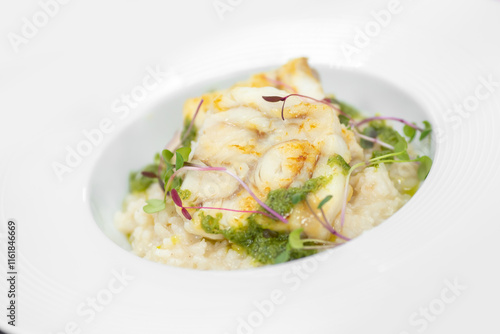 Grilled fish fillet on creamy risotto with greens and microgreens garnish