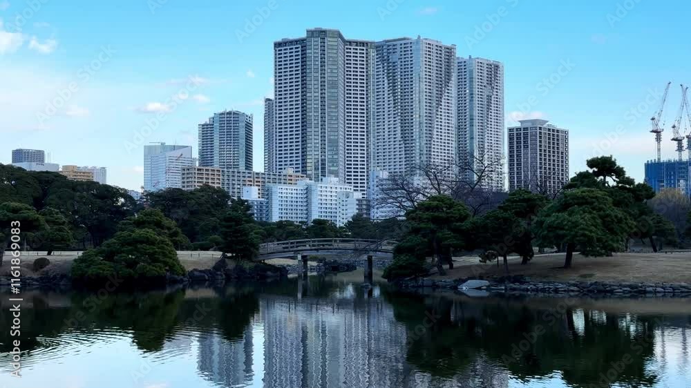A peaceful view of Hama Rikyu Gardens with a reflection pond and tall city buildings A peaceful view of Hama Rikyu Gardens with a reflection pond and tall city buildings