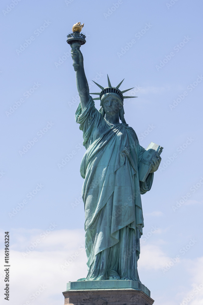 Fototapeta premium Closeup of the Statue of Liberty on the Liberty Island in New York against a blue sky and clouds.