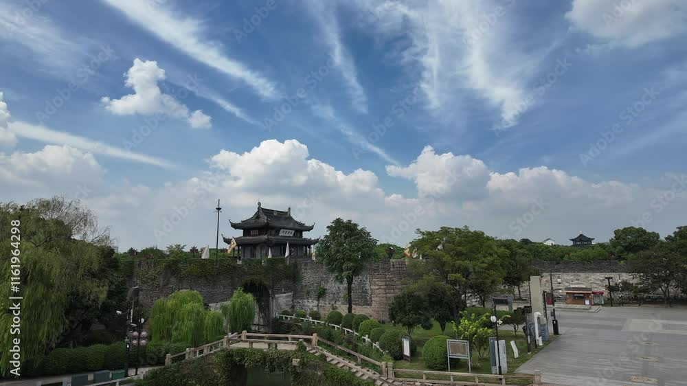 Time lapse of Suzhou Panmen City Gate showcasing blue sky and white clouds over tranquil landscapes Time lapse of Suzhou Panmen City Gate showcasing blue sky and white clouds over tranquil landscapes
