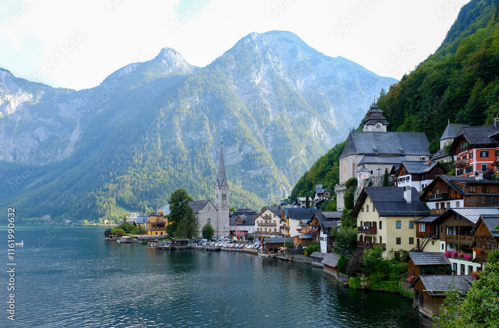 Idyllic village of Hallstatt, Austria, nestled along the shore of a serene alpine lake, with majestic mountains enveloping the village