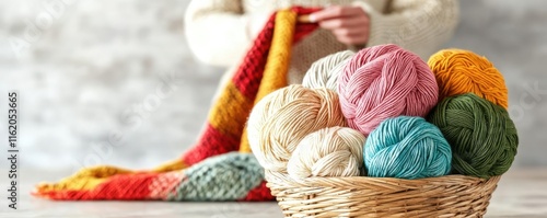 Colorful yarn balls in a basket with a person knitting a blanket in the background, showcasing a cozy crafting scene perfect for hobby enthusiasts.