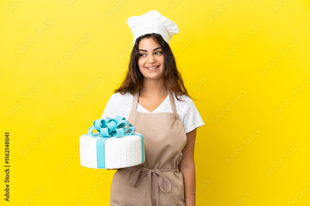 Young caucasian pastry chef woman with a big cake isolated on yellow background thinking an idea while looking up Young caucasian pastry chef woman with a big cake isolated on yellow background thinking an idea while looking up