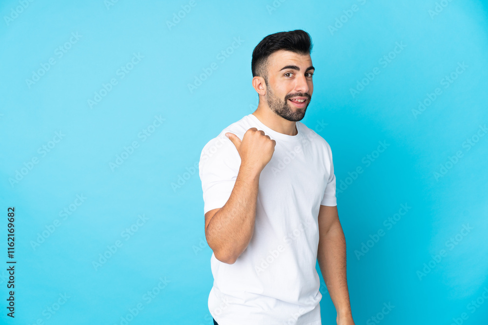 Caucasian man over isolated blue background pointing to the side to present a product Caucasian man over isolated blue background pointing to the side to present a product