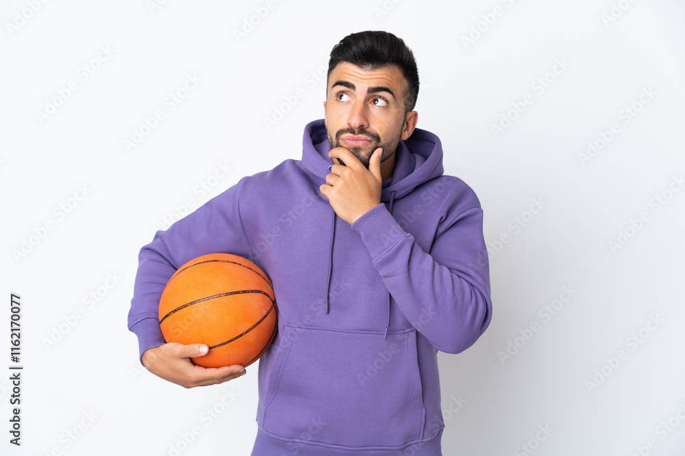 Man playing basketball over isolated white wall having doubts Man playing basketball over isolated white wall having doubts