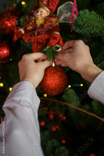 Decorating a Christmas tree with ornaments and ribbons during the holiday season at home