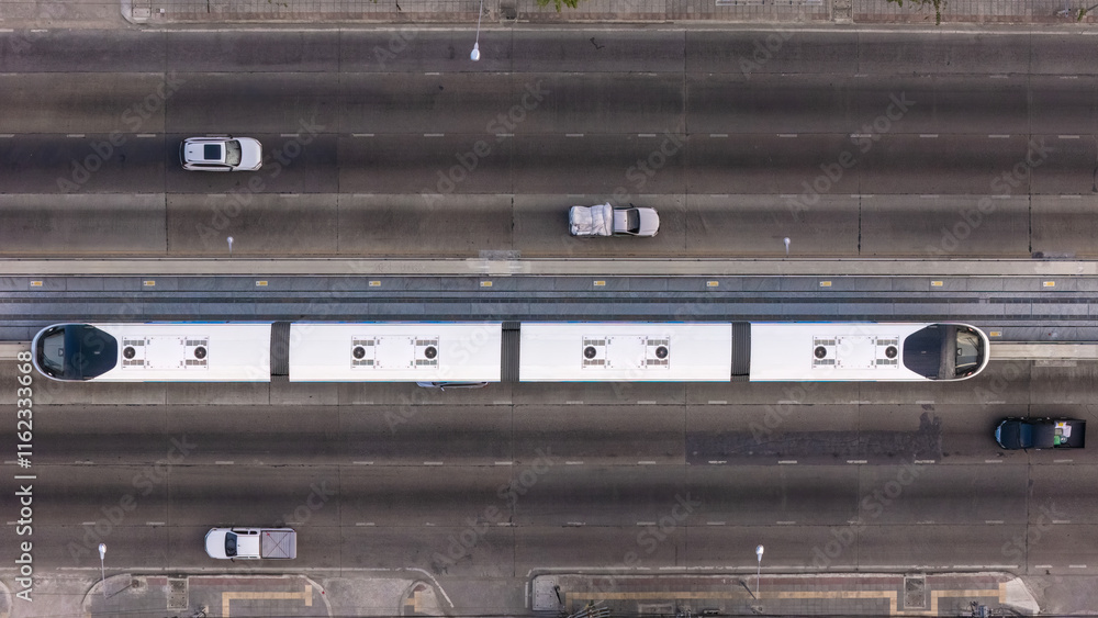 A top-down view of a multi-lane urban road with a central elevated rail track, surrounded by vehicles on both sides, showcasing modern city transportation infrastructure. A top-down view of a multi-lane urban road with a central elevated rail track, surrounded by vehicles on both sides, showcasing modern city transportation infrastructure.